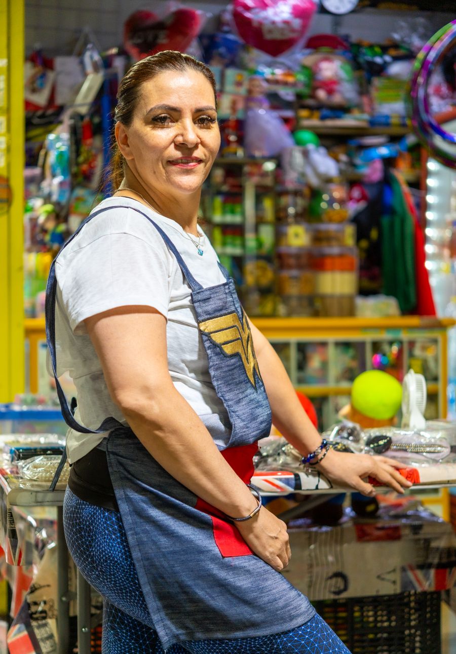 Comerciante en su local de variedades, rodeada de mercancía
