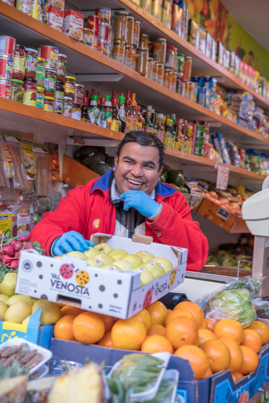 Comerciante sonriente atendiendo su puesto de fruta y víveres